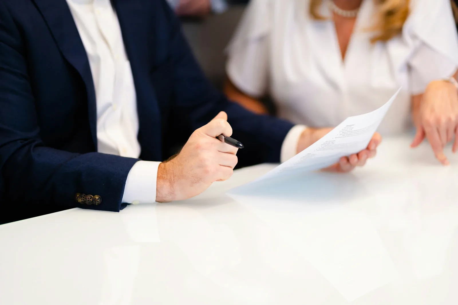 Professional reviewing printed documents at a white office table.