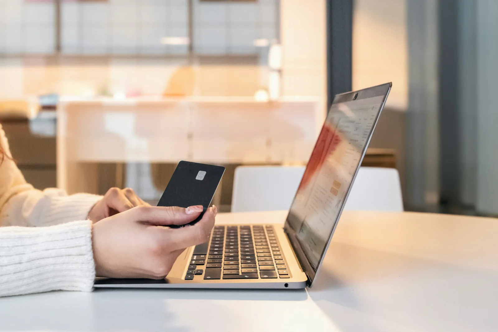 Person making a card payment while using a laptop.